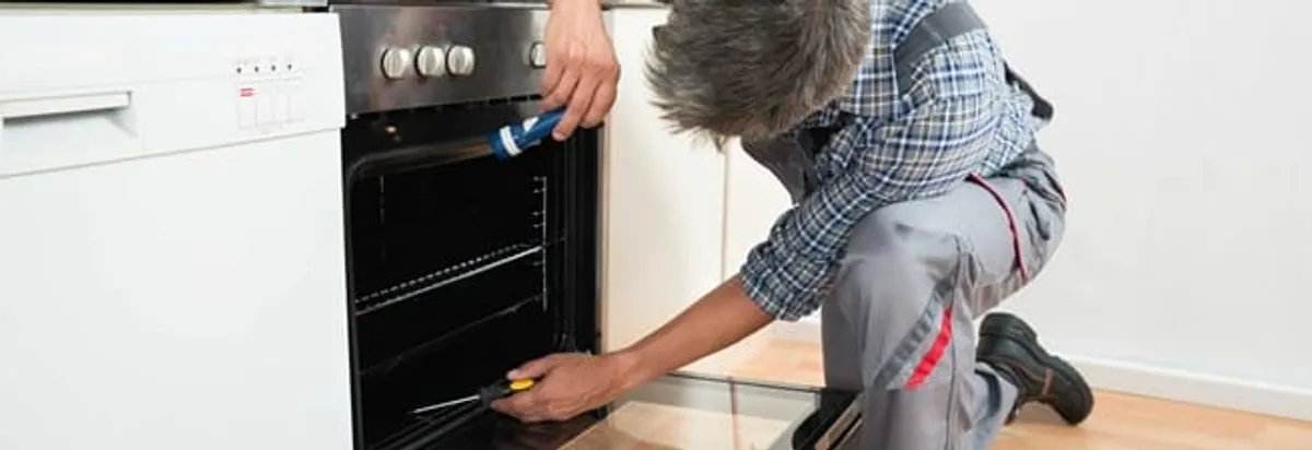 Oven repair technician inspecting and servicing an electric oven in Richmond, VA