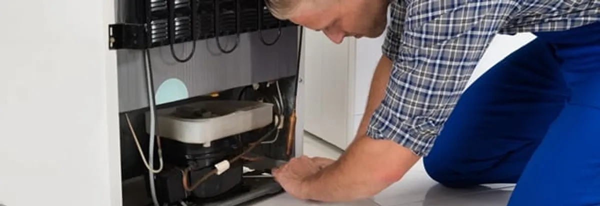 Refrigerator repair technician servicing the compressor and condenser area in Richmond, VA