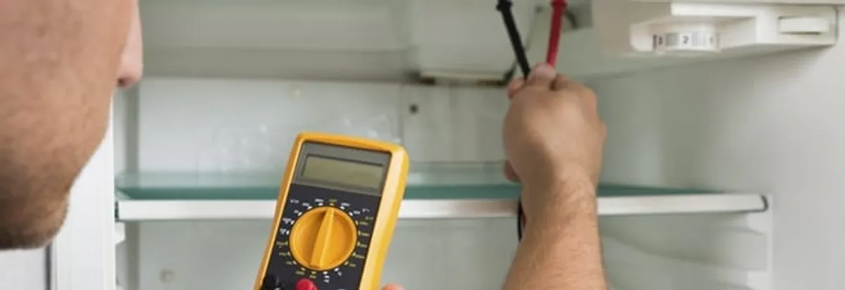 Refrigerator repair technician testing electrical components with a multimeter in Richmond, VA
