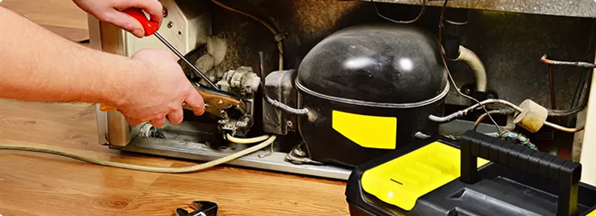 Refrigerator repair technician fixing the compressor and wiring in Richmond, VA